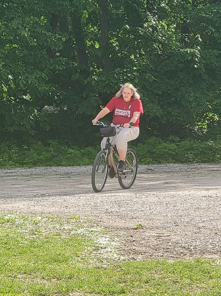 Woman in a red shirt riding a bike.