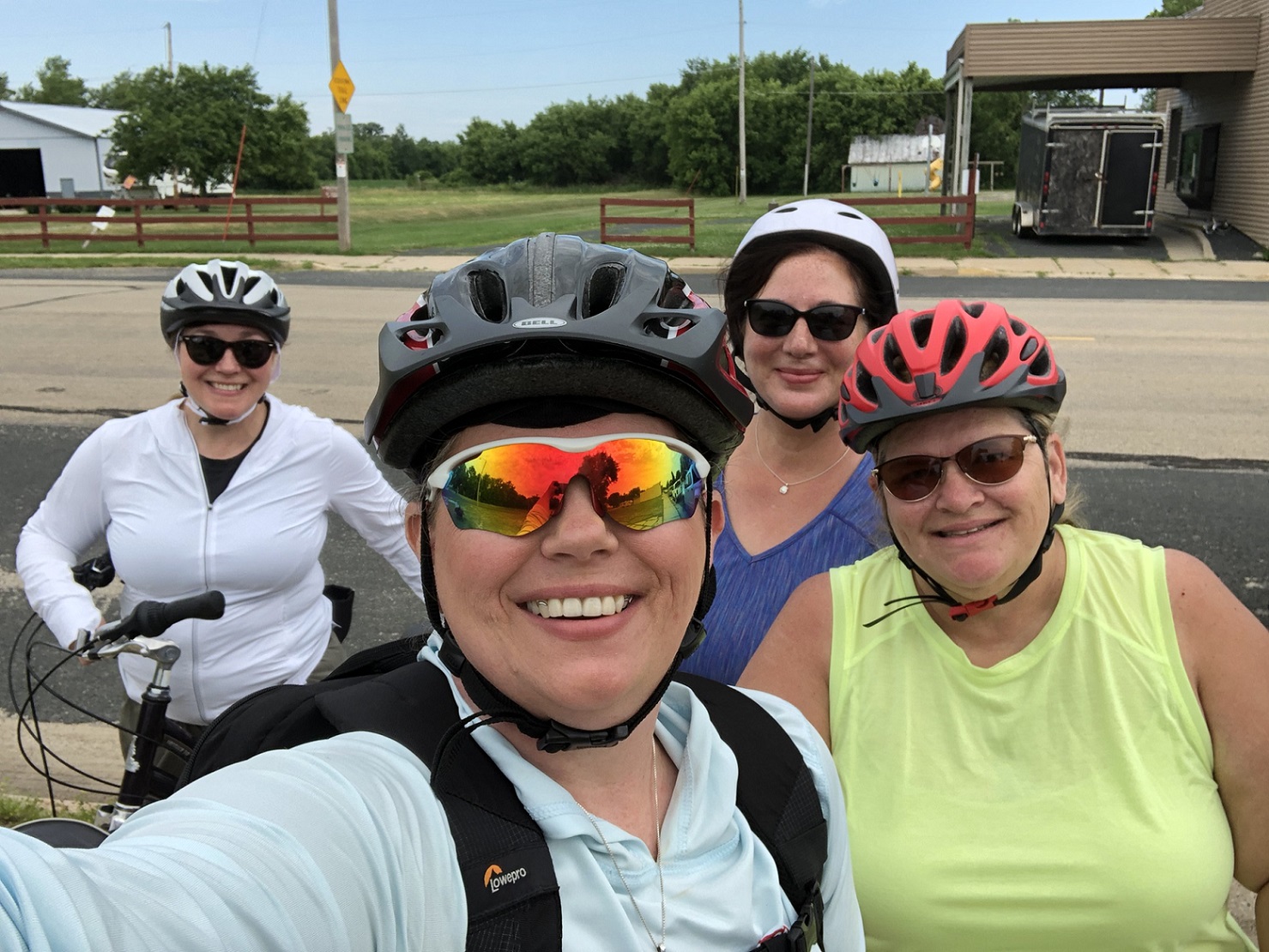 Four women wearing sunglasses and bike helmets