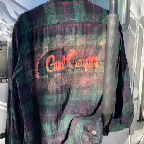 Green and blue flannel shirt with the Girl Camper Logo on the back side