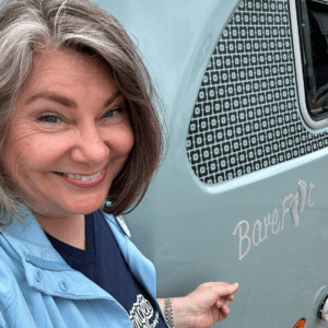 Girl Camper Lisa Dempsey is featured in front of a ndCamp Barefoot Trailer.  It is a small teal blue retro looking camper